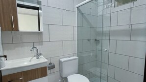 Un baño moderno con inodoro, lavabo y cabina de ducha de vidrio.