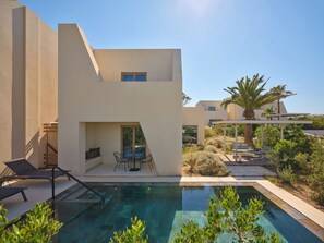 A modern house with a swimming pool, outdoor seating, and a garden.