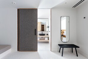 A modern bathroom with a large mirror, a black bench, and a visible sink area. - Nous Santorini (Santorini)