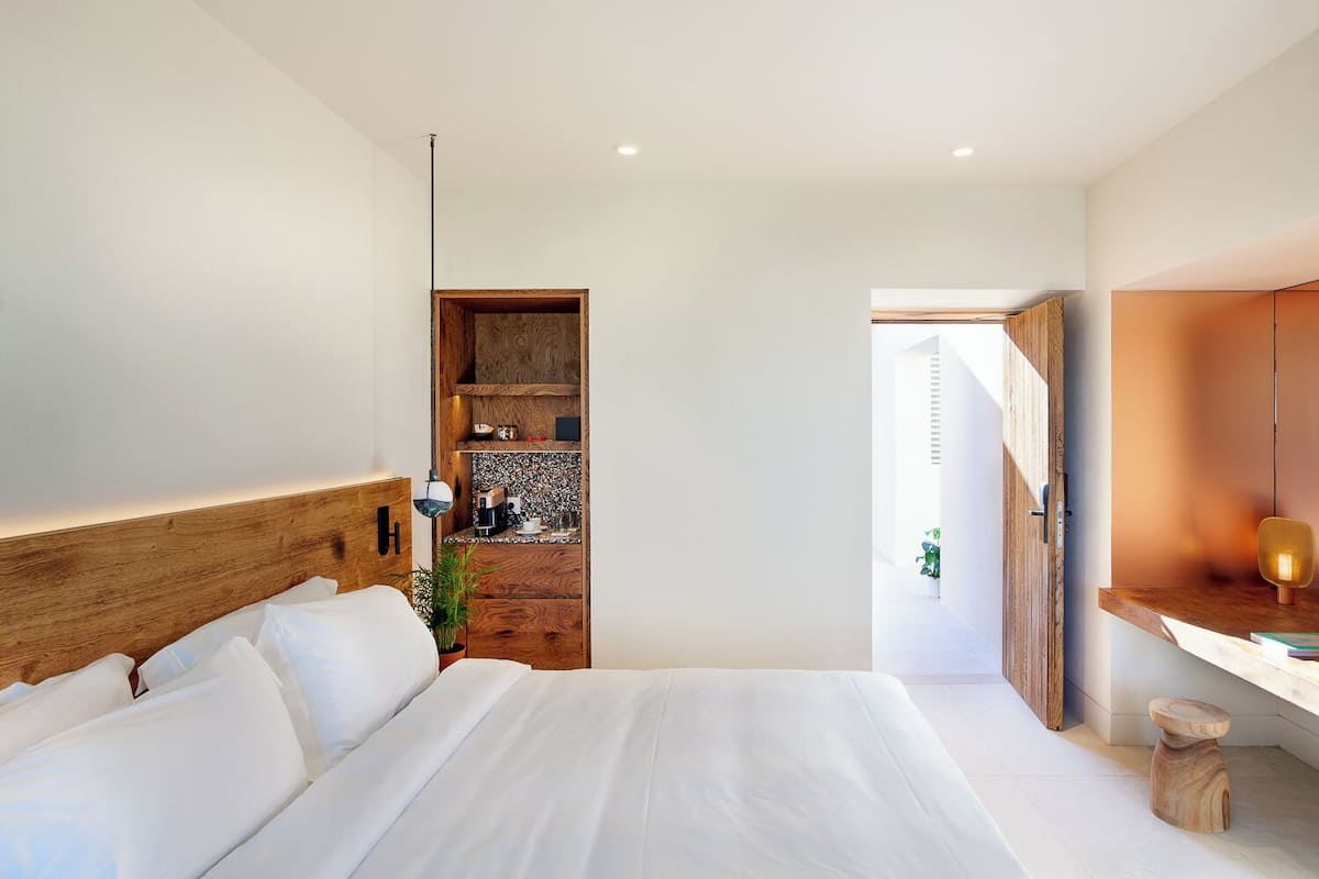 Un dormitorio moderno con una cama grande, cabecera de madera, estanterías empotradas y una pequeña zona de escritorio.
