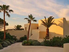 A modern building with palm trees and a paved pathway. - Nous Santorini (Santorini)