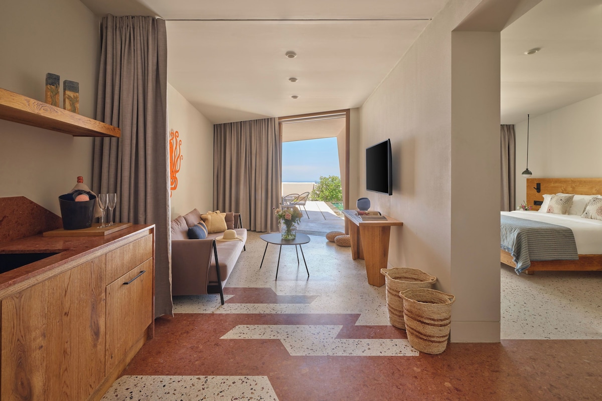 Une chambre d’hôtel moderne équipée d’un canapé, d’une table à manger, d’un lit, d’une télévision et offrant une vue sur l’extérieur.