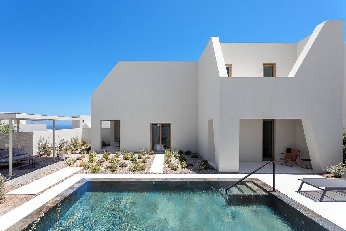 Un edificio moderno con piscina, zona de estar exterior y cielo azul despejado.