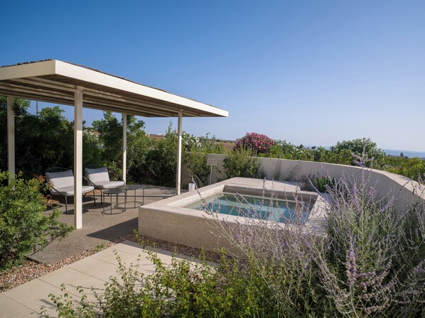 Un espacio al aire libre cubierto con piscina, sillas de descanso y una pérgola.