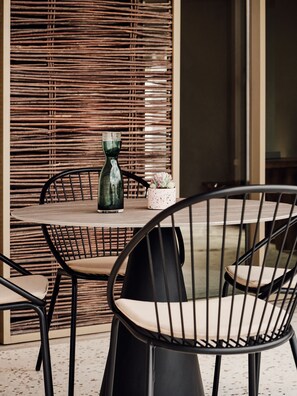 A round table with two chairs, a green vase, and a small potted plant. - Nous Santorini (Santorini)