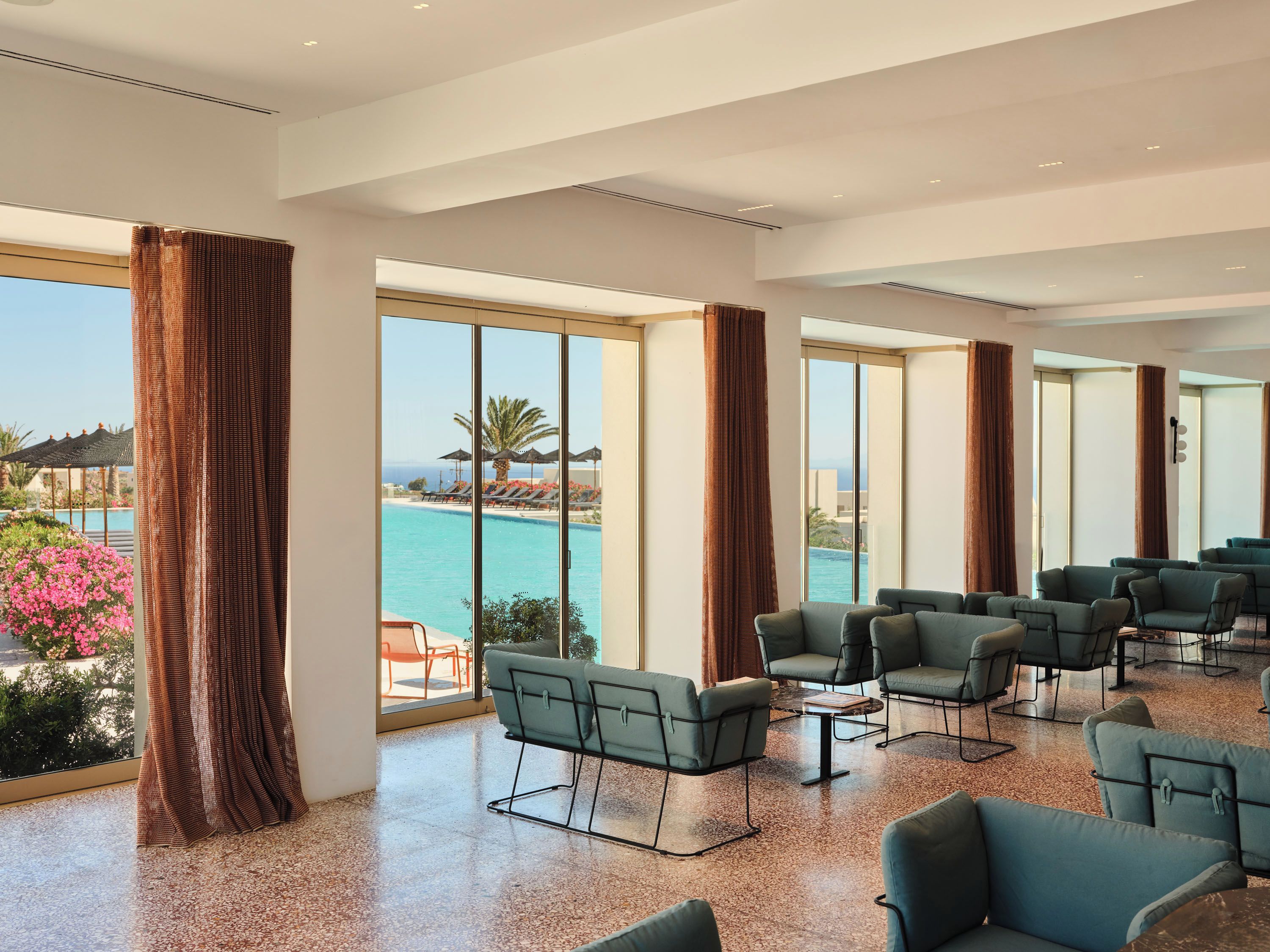 A spacious room with large windows, a pool view, and multiple seating areas.