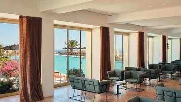A spacious room with large windows, a pool view, and multiple seating areas.