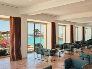 Una habitación amplia con ventanas grandes, vista a la piscina y varias zonas de estar.