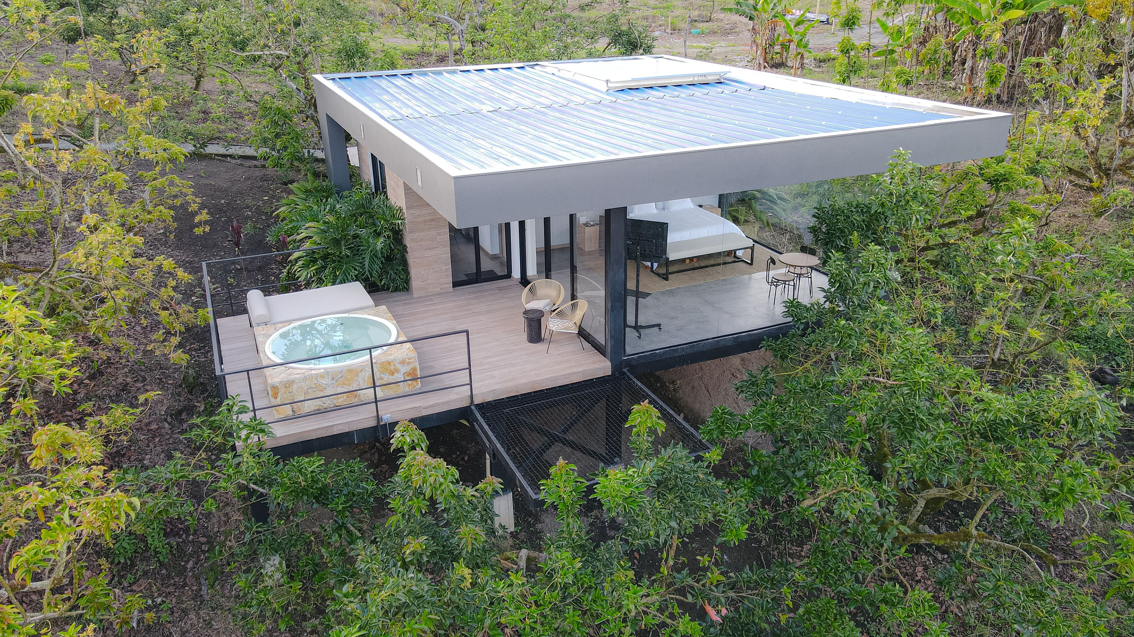Una casa moderna con hidromasaje acristalado, mobiliario exterior y techo con paneles solares.
