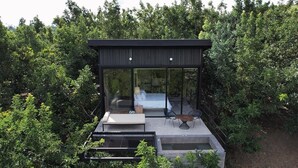 Une chambre moderne, entièrement vitrée, comprenant un lit, deux chaises et une petite table.