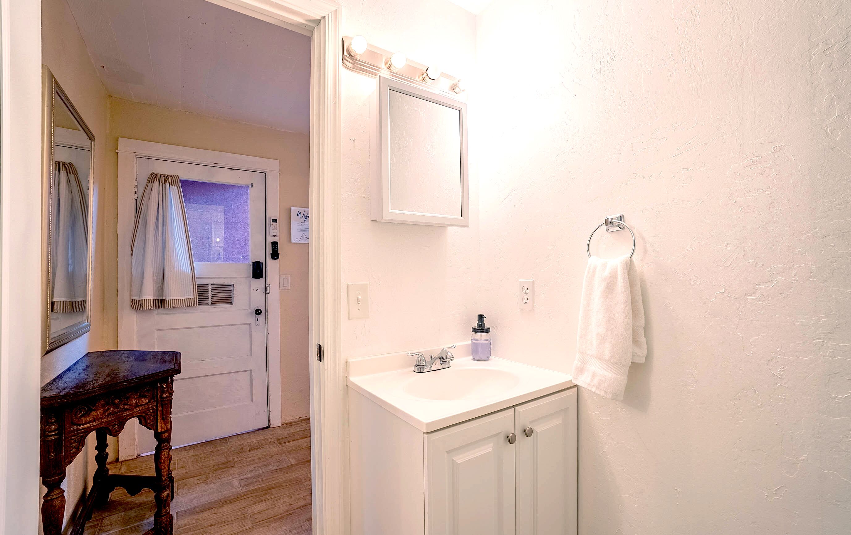 A bathroom with a white sink, a mirror, and a towel hanging on a rack.