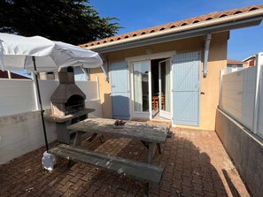 An outdoor patio with a stone oven, a wooden table, and a white umbrella.