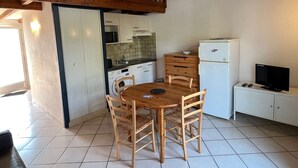 Une cuisine compacte comprenant une table à manger, des chaises, un four à micro-ondes, un réfrigérateur et un téléviseur.