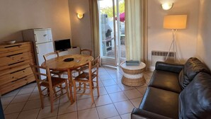 Un salon chaleureux avec une table à manger en bois, des chaises, un canapé en cuir, une petite table ronde, une lampe et un téléviseur.