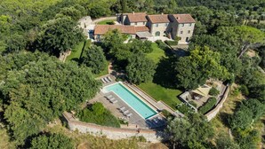 Une vue aérienne d’un vaste domaine comprenant plusieurs bâtiments, une piscine et une végétation luxuriante.