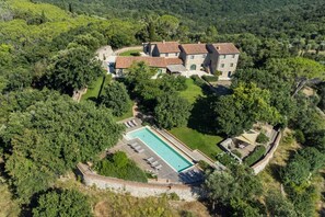 An aerial view of a large estate with multiple buildings, a swimming pool, and lush greenery.