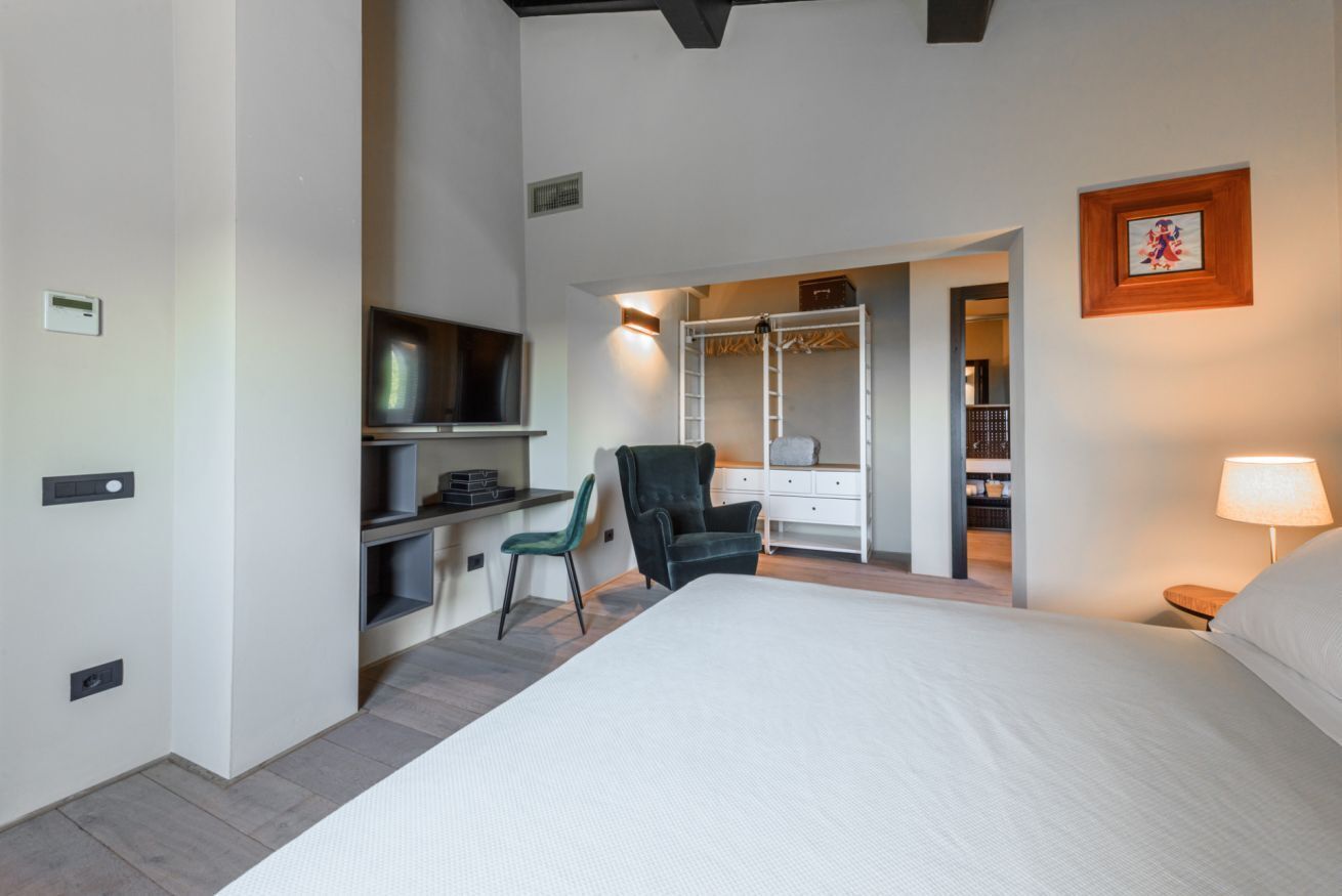 Un dormitorio con cama, escritorio, silla, armario y televisor.