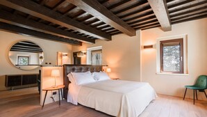 Une chambre à coucher avec un lit, des lampes de chevet, un miroir rond, une fenêtre et un fauteuil vert.