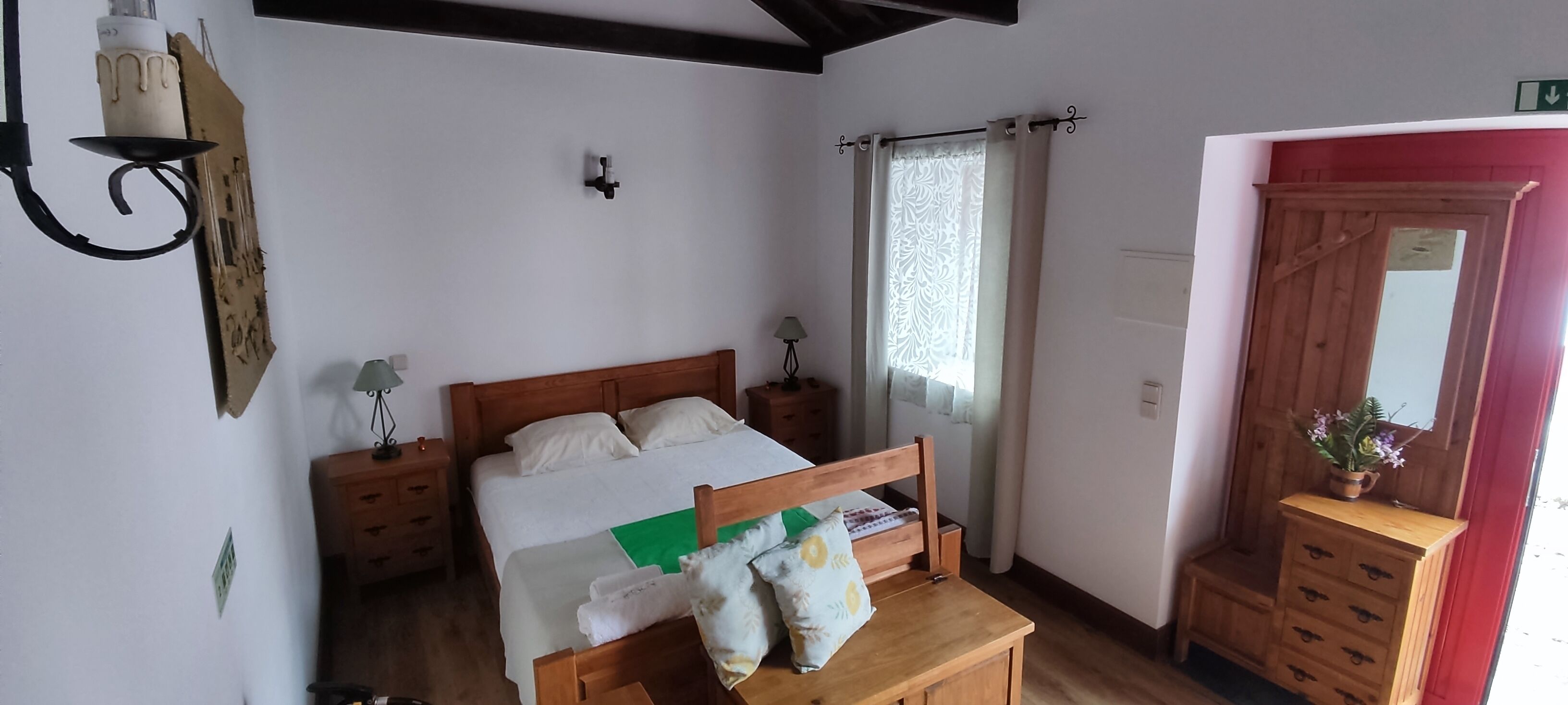 Una camera da letto con un letto di legno, comodini, un tavolino e una cassettiera in legno.