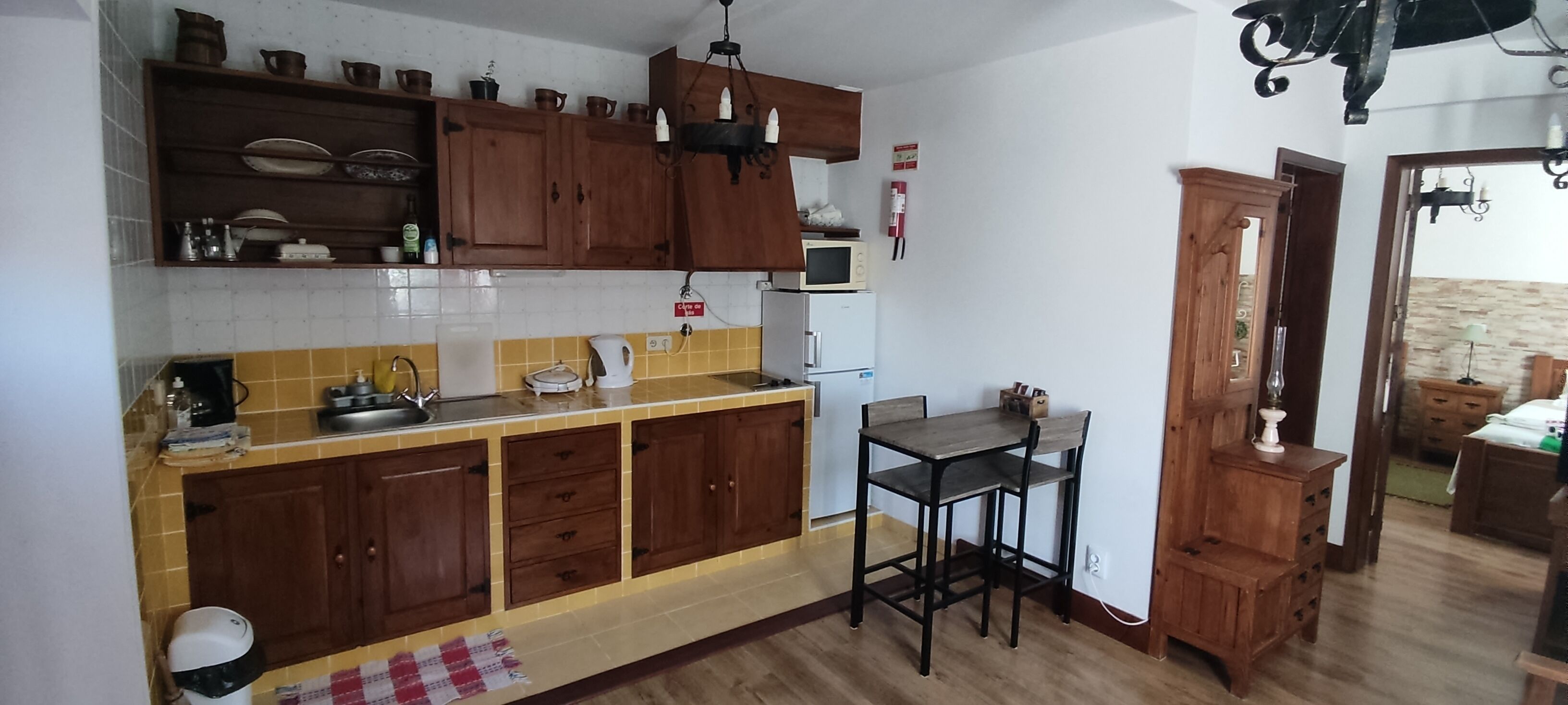 Una cocina con armarios de madera, un microondas y un lavamanos.