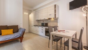 Eine moderne Wohnung mit Küchenzeile, Essbereich, Sofa und Wand-Fernseher.