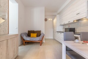 A modern kitchen with a dining area, a sofa with cushions, and a wooden cabinet.