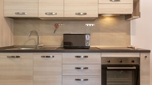 Eine moderne Küche mit eingebauter Mikrowelle, Edelstahlgeräten und hellen Holzschränken.