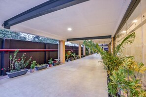 A covered walkway with potted plants and a red pipe. - Mount Amara Hotel & Spa (Jalpaiguri)