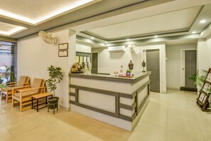 A reception area with a counter, chairs, and potted plants. - Mount Amara Hotel & Spa (Jalpaiguri)