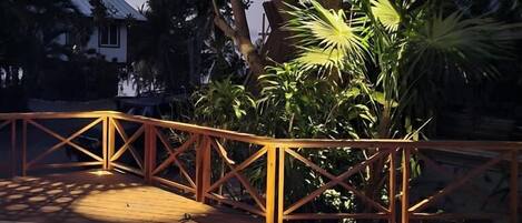 A pool area with a wooden deck, a metal railing, and hanging lanterns.