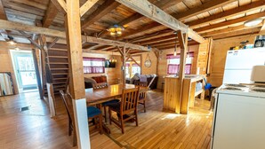 A rustic wooden interior with a dining area, kitchen, and a staircase.