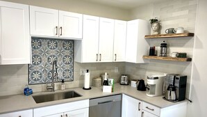 Eine moderne Küche mit weißen Schränken, einer gemusterten Spritzschutzwand und Edelstahlgeräten.