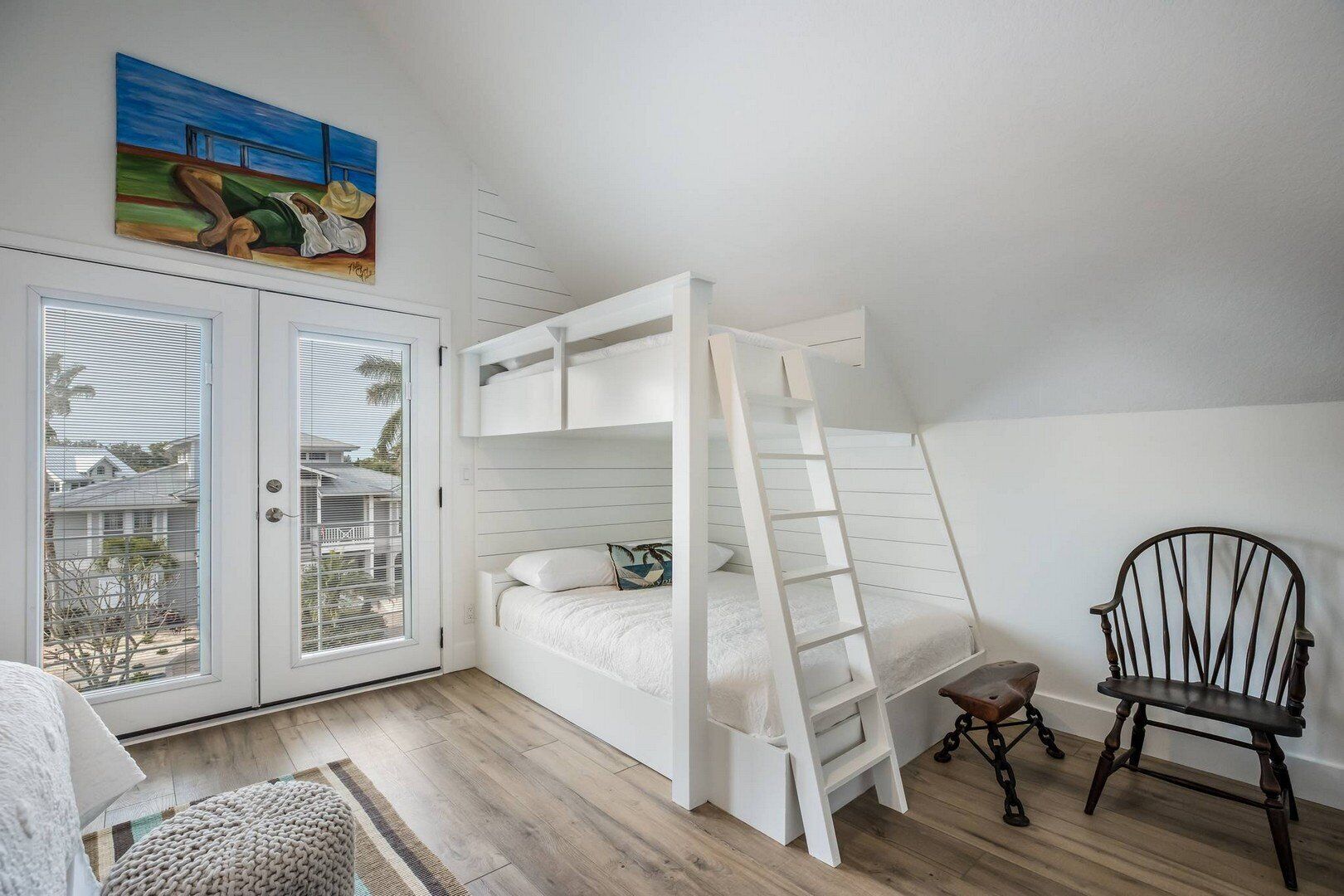 Habitación con literas, una escalera, una silla y un cuadro en la pared.