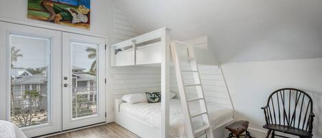 Habitación con literas, una escalera, una silla y un cuadro en la pared.