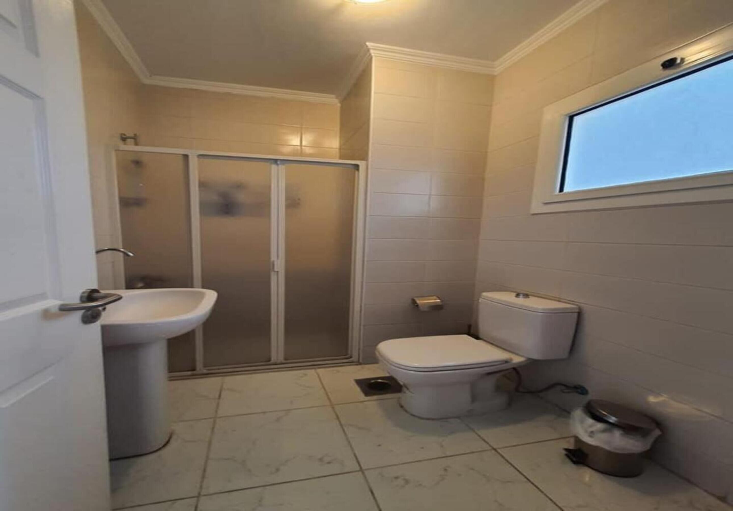 A bathroom with a toilet, sink, and shower enclosure.