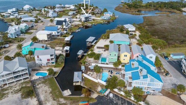 Vista aérea de una zona residencial costera con casas, un canal estrecho y una playa.