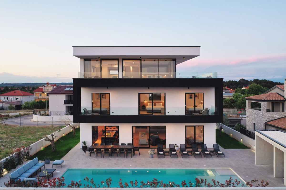 Une maison moderne à deux étages, dotée d’une piscine, d’un espace de détente extérieur et offrant une vue sur le quartier environnant.