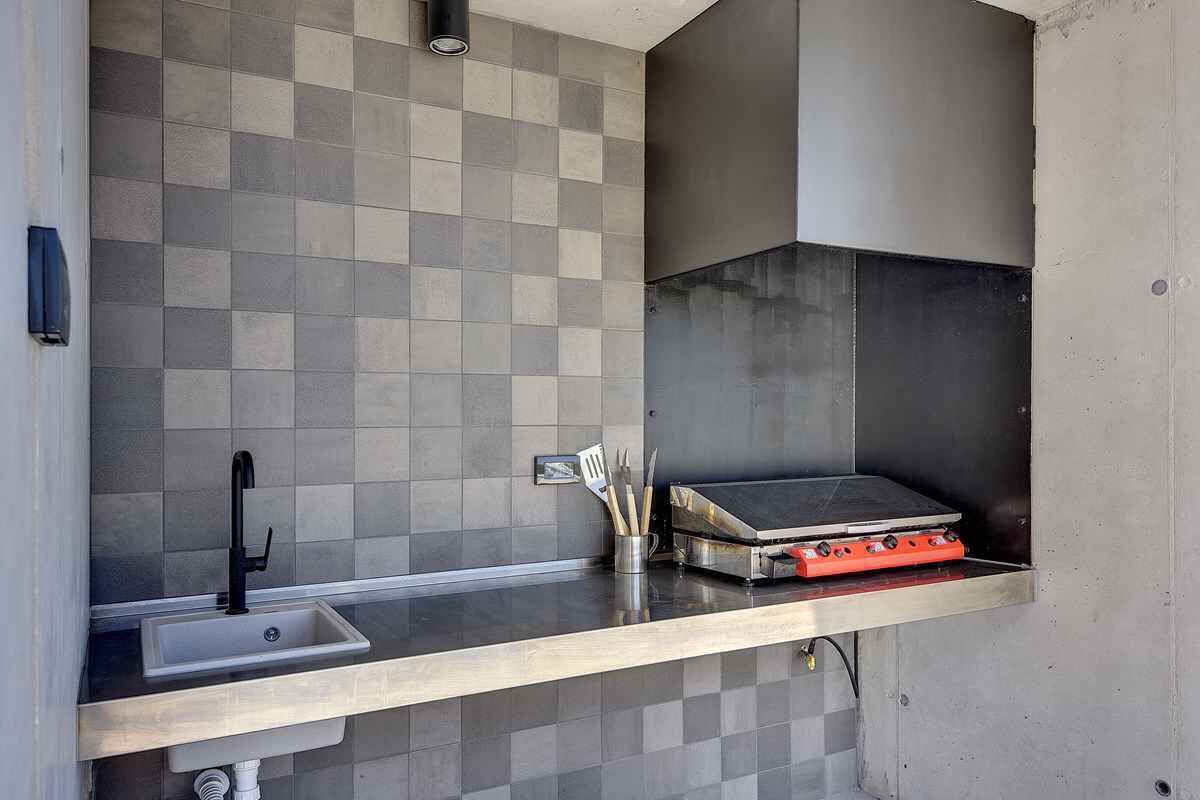 A kitchen with a sink, a gas stove, and a tiled backsplash.