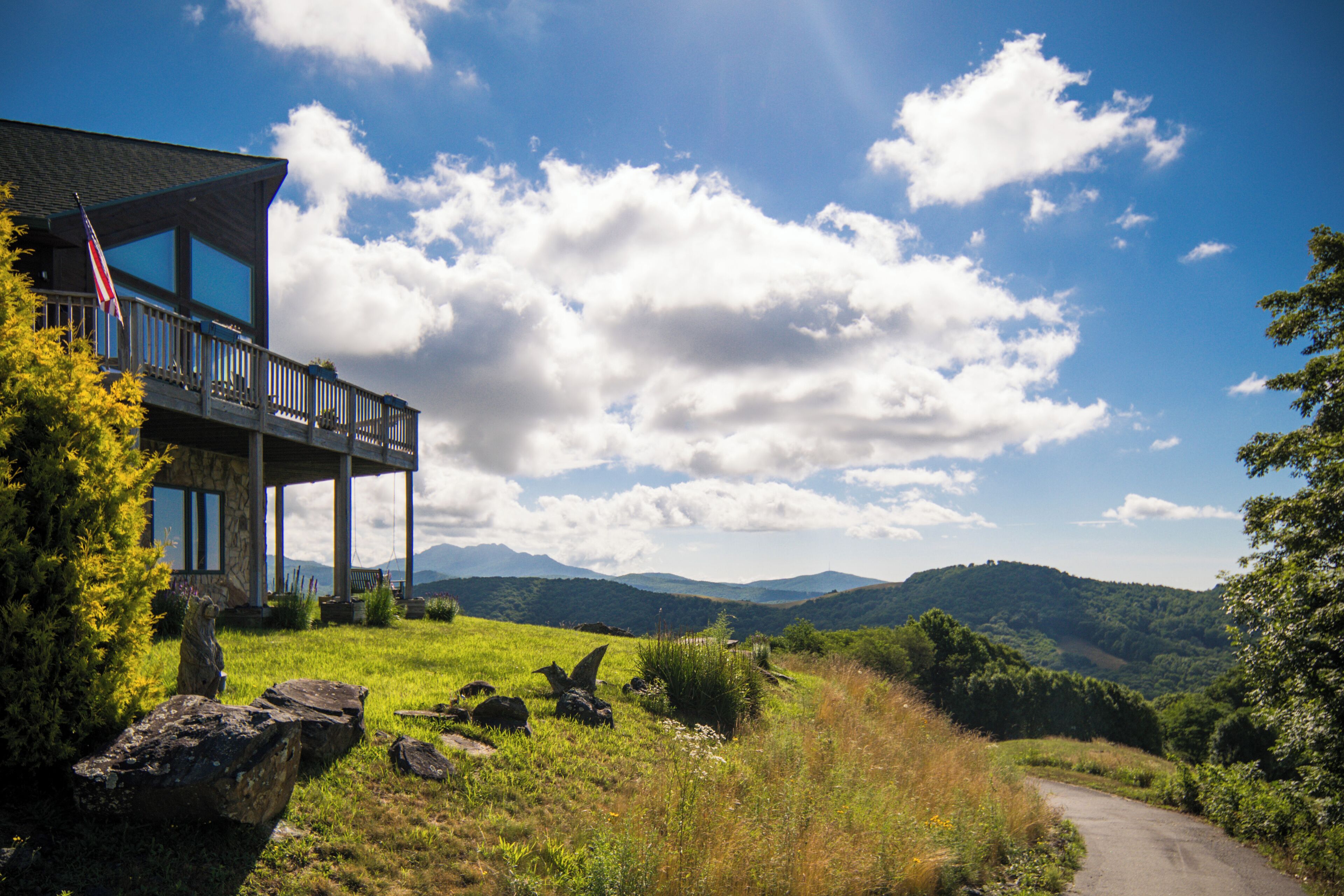 Ein Haus mit Balkon, umgeben von einer grünen Landschaft und Bergen im Hintergrund.