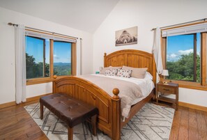 Ein Schlafzimmer mit einem großen Bett, einem Holzkopfende, einem Nachttisch und einer Bank.