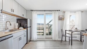 Eine moderne Küche mit weißen Schränken, einem Geschirrspüler und einem Essbereich mit Tisch und Stühlen.