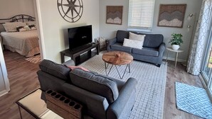 A living room with a sofa, coffee table, TV, and artwork on the walls. - POOL, PARKING, 2BR 2 BA, walk to town! (Rehoboth Beach)