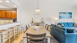 Un comedor con una mesa de madera, sillas y una lámpara colgante.
