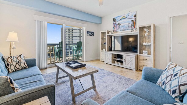 Una sala de estar con sofá, mesa de centro, televisor y balcón con vistas.