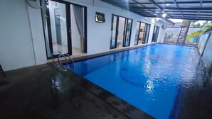 Une piscine intérieure à l’eau claire, entourée de fenêtres et de portes.