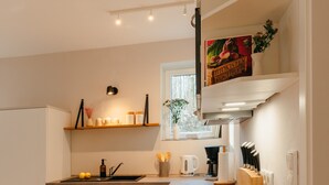 A modern kitchen with white cabinetry, a wooden countertop, and a bowl of fruit. - The vacation apartment with three terraces is located between the forest and the lake (Ratzeburg)