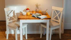 A dining table with two white chairs, a wooden floor, and a hanging light fixture. - The vacation apartment with three terraces is located between the forest and the lake (Ratzeburg)
