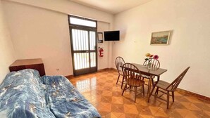 Une pièce comprenant un lit, une table à manger avec des chaises, un téléviseur fixé au mur et un tableau.
