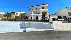 Un immeuble résidentiel à plusieurs étages, doté de balcons, d’une entrée sécurisée et d’une allée pavée.