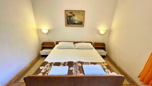 Un dormitorio pequeño y ordenado con una cama individual, dos mesitas de noche y un cuadro colgado en la pared.